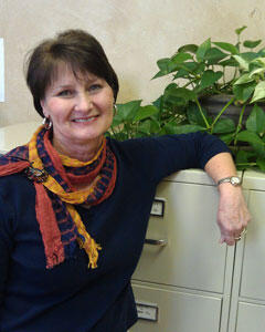 Susan wearing a blue shirt with red, blue and gold scarf