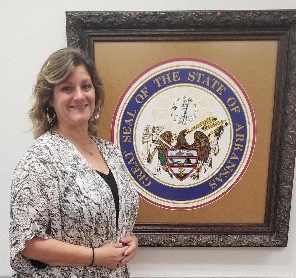 Penny standing in front of Arkansas State Seal