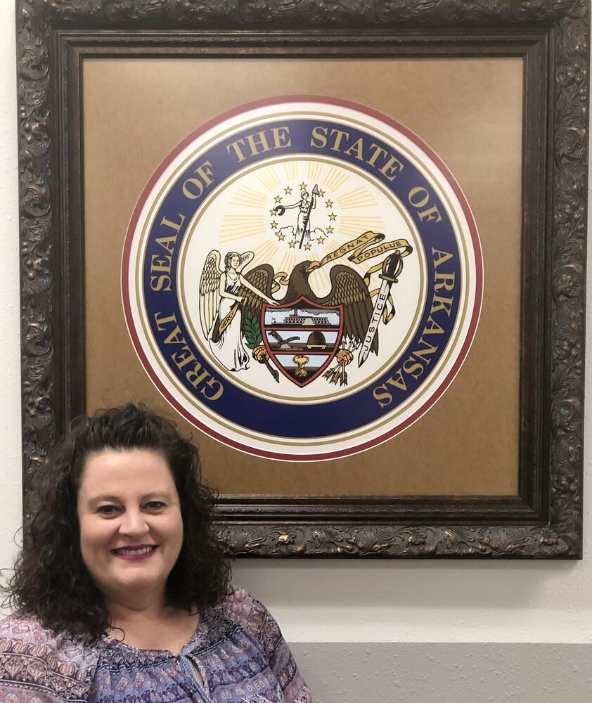 Mary in front of Arkansas State Seal
