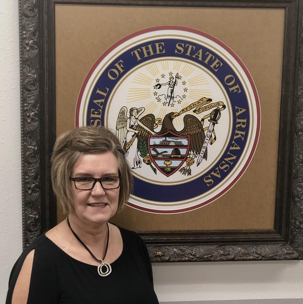 Tammy standing in front of Arkansas State Seal